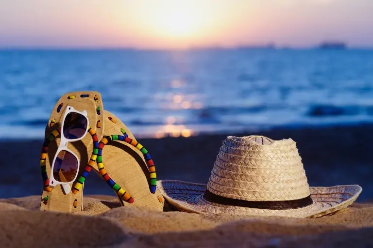 Beach mud a cap and slippers are placed with a sun glass representing things to do in August Long Weekends 